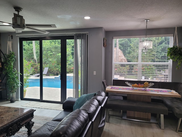 interior space featuring ceiling fan with notable chandelier, a healthy amount of sunlight, and light wood-type flooring