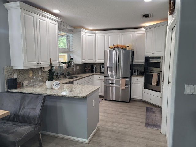 kitchen with white cabinets, tasteful backsplash, kitchen peninsula, and stainless steel appliances