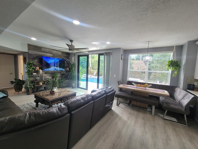 living room with a textured ceiling, light wood-type flooring, and ceiling fan