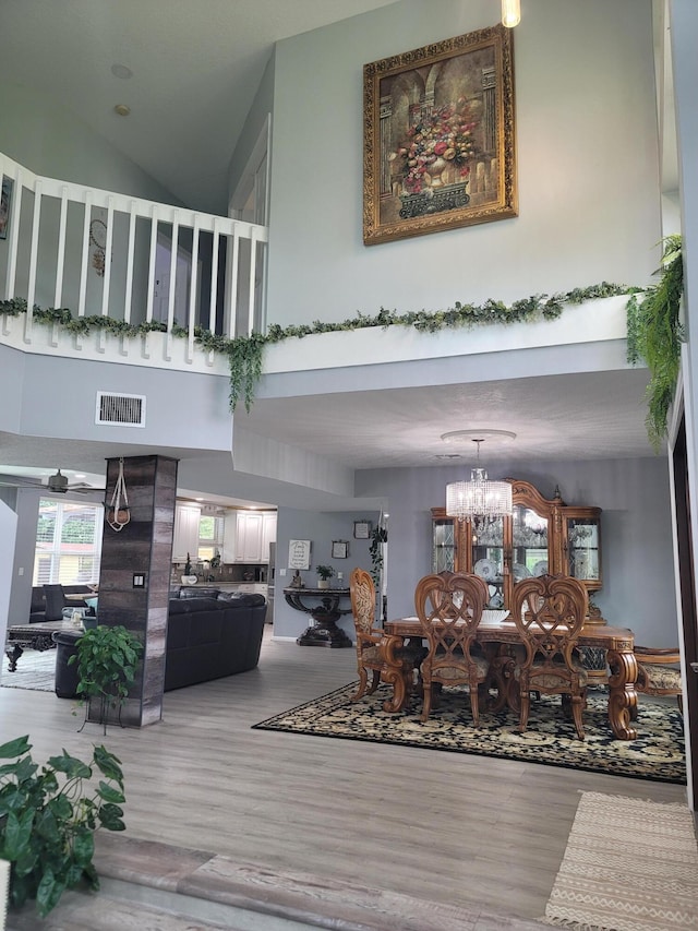 interior space with ceiling fan with notable chandelier, wood-type flooring, and a high ceiling