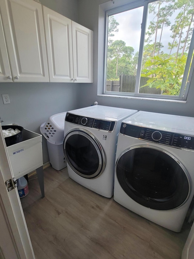 laundry area featuring light hardwood / wood-style floors, sink, cabinets, and washing machine and clothes dryer