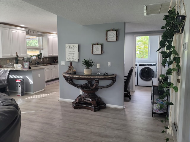 dining space featuring separate washer and dryer, light wood-type flooring, and a textured ceiling