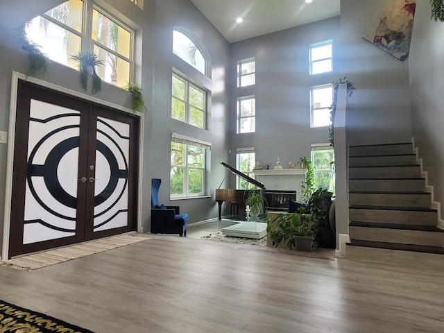 foyer entrance with plenty of natural light, a high ceiling, french doors, and hardwood / wood-style flooring