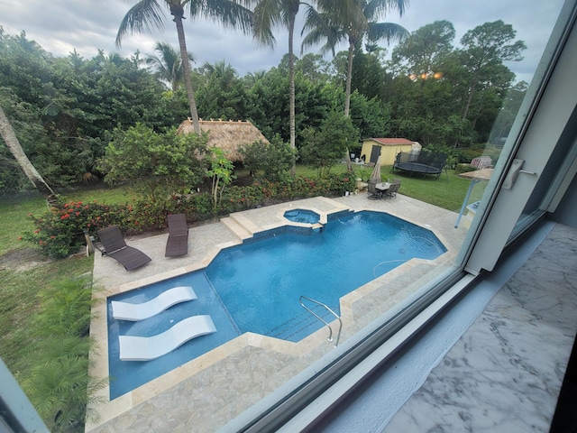 view of swimming pool featuring a patio area, an in ground hot tub, and a storage shed