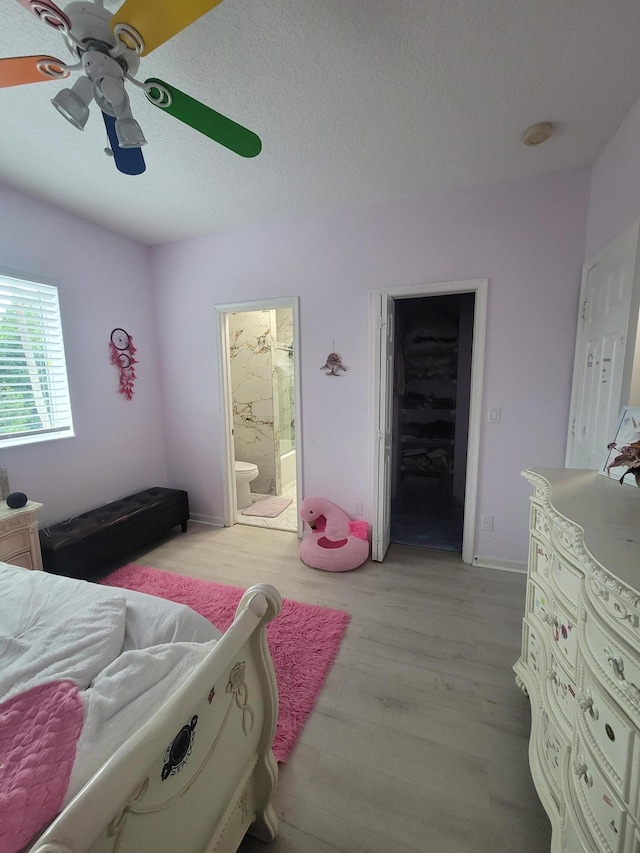 bedroom with a spacious closet, a closet, ceiling fan, ensuite bath, and light wood-type flooring