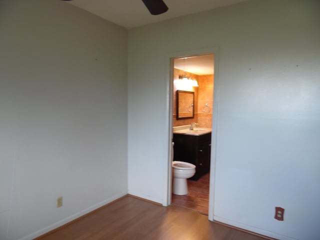 unfurnished bedroom featuring ensuite bathroom, ceiling fan, sink, and dark hardwood / wood-style flooring