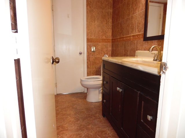 bathroom with tile walls, toilet, tile floors, and vanity