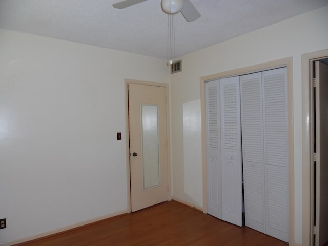 unfurnished bedroom featuring dark hardwood / wood-style flooring, a closet, and ceiling fan