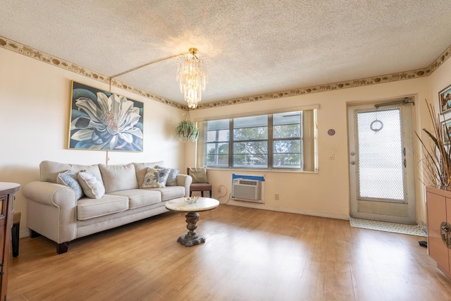 living room featuring wood-type flooring, a textured ceiling, a chandelier, and a wall mounted air conditioner