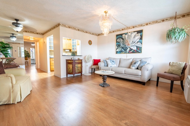 living room with an inviting chandelier, hardwood / wood-style floors, and a textured ceiling