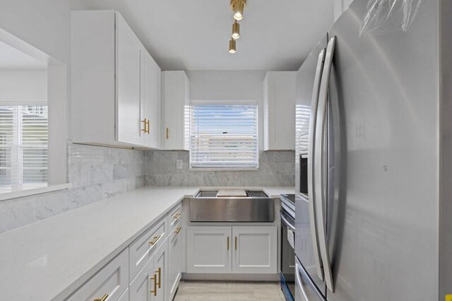 kitchen featuring white cabinets, stainless steel appliances, decorative backsplash, and sink