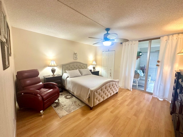 bedroom with multiple windows, ceiling fan, access to exterior, light hardwood / wood-style flooring, and a textured ceiling