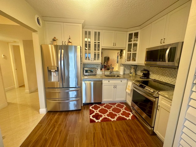 kitchen with tasteful backsplash, stainless steel appliances, hardwood / wood-style flooring, and white cabinetry