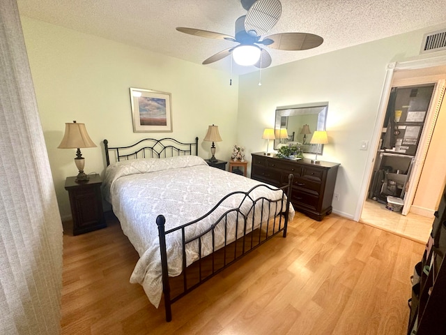 bedroom with a textured ceiling, ceiling fan, and light hardwood / wood-style flooring