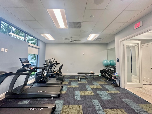 gym with a paneled ceiling, carpet, and ceiling fan