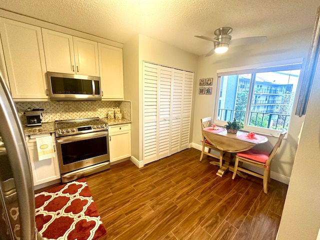 kitchen with white cabinetry, stainless steel appliances, ceiling fan, and dark hardwood / wood-style flooring