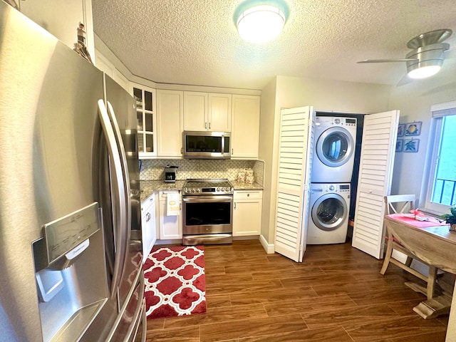 kitchen with ceiling fan, stacked washer and dryer, white cabinets, stainless steel appliances, and tasteful backsplash