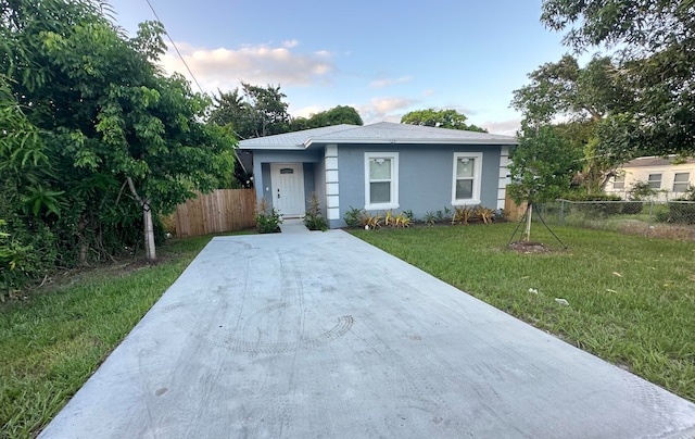 view of front of house featuring a front lawn, fence, and stucco siding