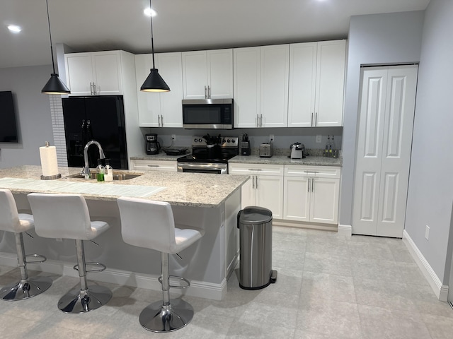 kitchen with appliances with stainless steel finishes, a sink, white cabinetry, and a kitchen breakfast bar