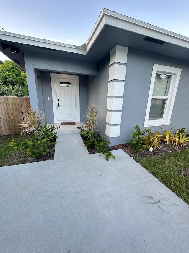 doorway to property with fence and stucco siding