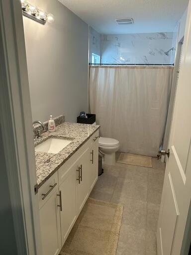 bathroom with visible vents, toilet, tile patterned floors, curtained shower, and vanity