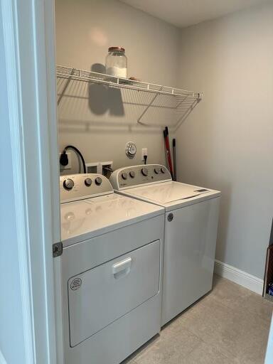 laundry room featuring laundry area, baseboards, and washing machine and clothes dryer