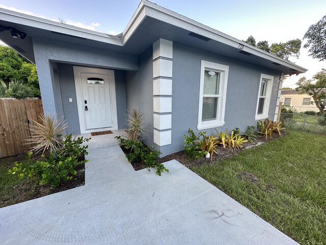 view of exterior entry featuring fence and stucco siding