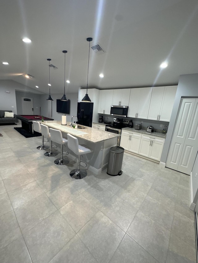 kitchen with lofted ceiling, visible vents, appliances with stainless steel finishes, white cabinetry, and light stone countertops