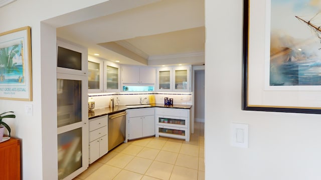 kitchen with white cabinetry, sink, stainless steel dishwasher, crown molding, and a tray ceiling