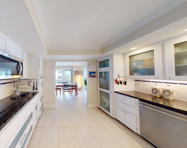 kitchen with white cabinets, light tile patterned floors, appliances with stainless steel finishes, and dark stone counters