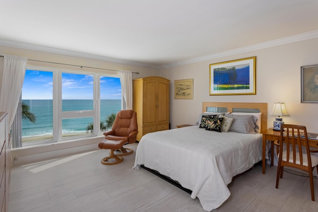 bedroom featuring a view of the beach, a water view, ornamental molding, and light hardwood / wood-style flooring