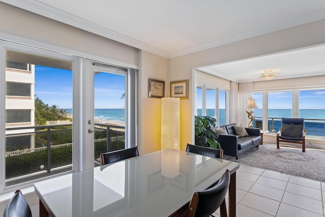 dining space featuring a beach view, a water view, light tile patterned floors, and crown molding