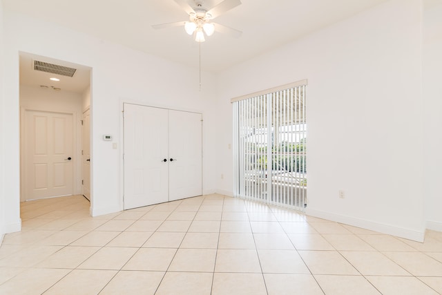 unfurnished bedroom with light tile floors, a closet, ceiling fan, and access to outside