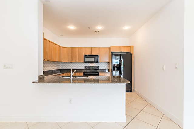 kitchen with dark stone counters, light tile flooring, tasteful backsplash, black appliances, and sink