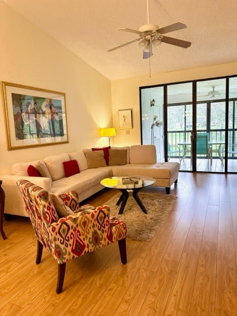 living room featuring ceiling fan, light hardwood / wood-style flooring, and lofted ceiling