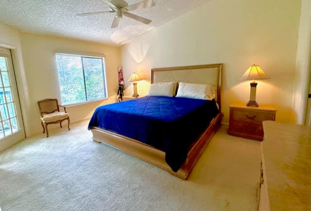 bedroom with ceiling fan, carpet, and a textured ceiling