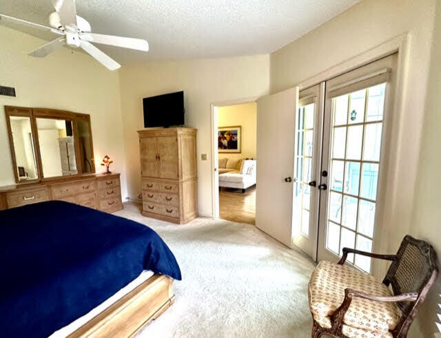 bedroom featuring multiple windows, french doors, lofted ceiling, ceiling fan, and light carpet