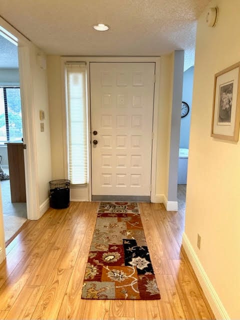 entrance foyer with a textured ceiling and light hardwood / wood-style flooring