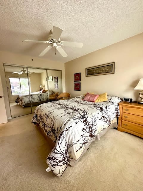 carpeted bedroom with ceiling fan, a closet, and a textured ceiling