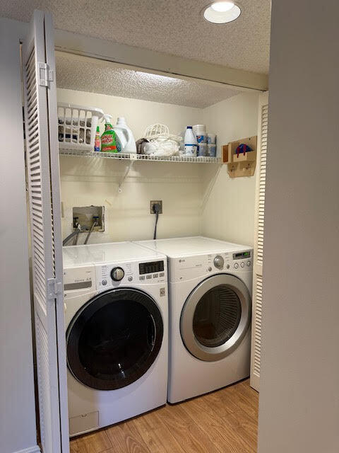 washroom with light wood-type flooring, a textured ceiling, and separate washer and dryer