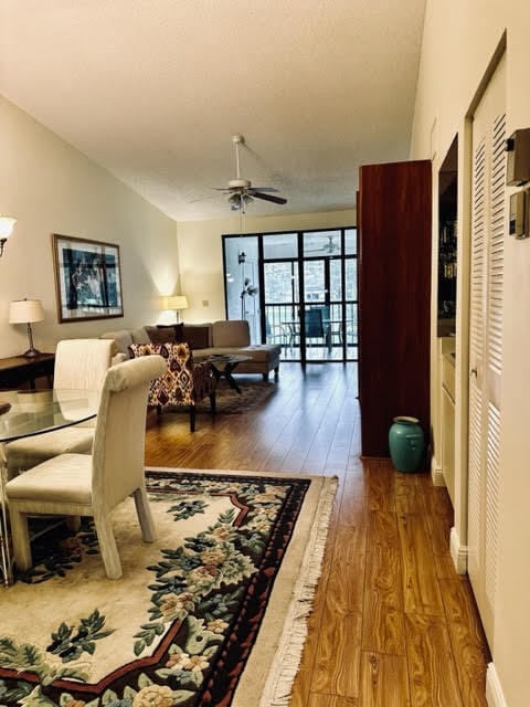 living room featuring ceiling fan, vaulted ceiling, and wood-type flooring