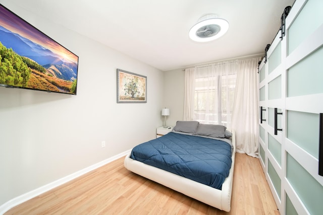 bedroom featuring a barn door and hardwood / wood-style floors