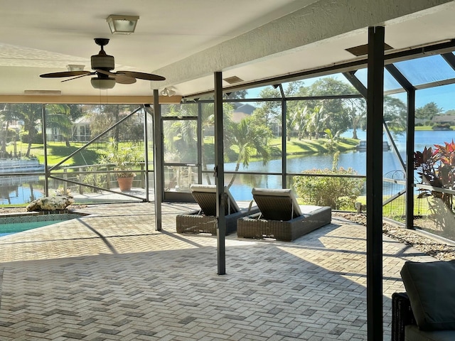 unfurnished sunroom featuring ceiling fan and a water view