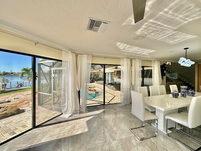 dining space with a wealth of natural light, a textured ceiling, and a water view