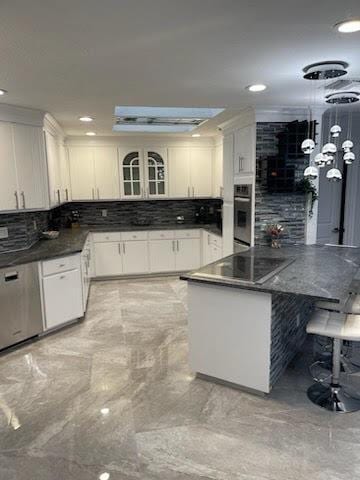 kitchen featuring decorative backsplash, white cabinets, and hanging light fixtures