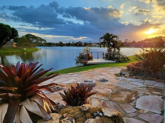 patio terrace at dusk featuring a water view