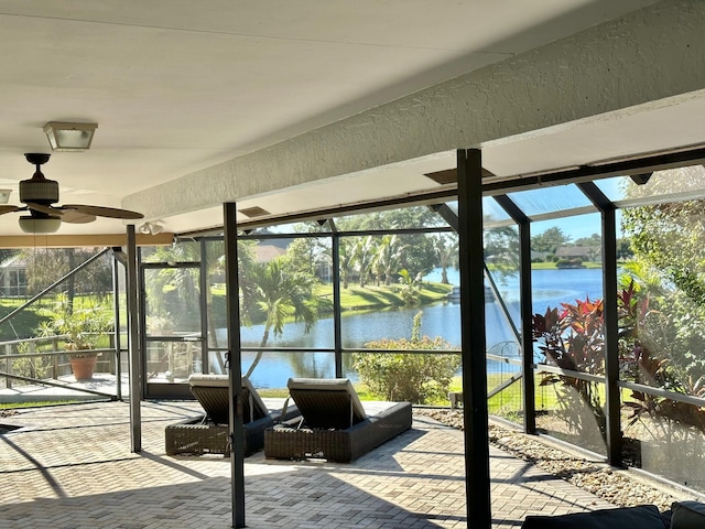 unfurnished sunroom featuring ceiling fan and a water view