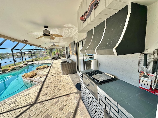 exterior space featuring glass enclosure, a patio area, ceiling fan, and a water view