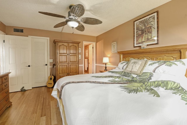 bedroom with a textured ceiling, ceiling fan, and light hardwood / wood-style flooring