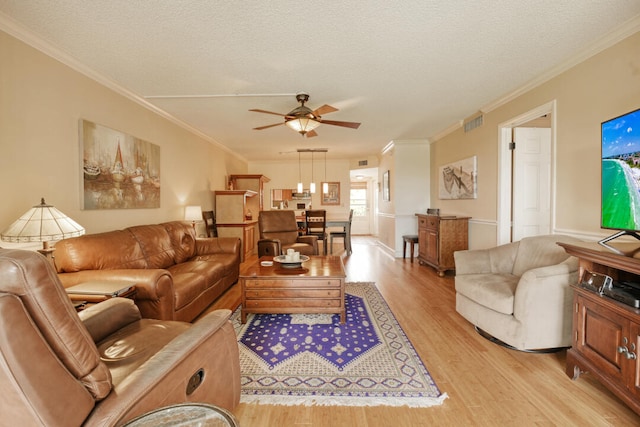 living room with light hardwood / wood-style flooring, a textured ceiling, ceiling fan, and crown molding